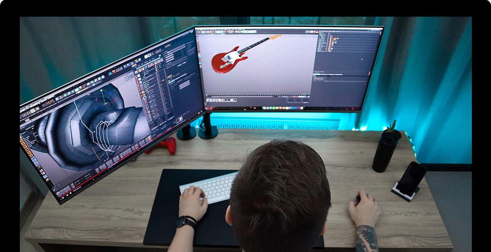 Man sitting in front of workstation with 3d model of a guitar